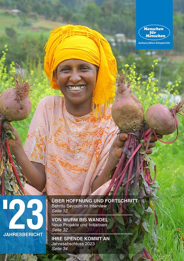 Cover of the annual report by Menschen für Menschen, which shows a woman sitting in a field, holding beets in her hand and smiling 