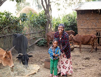 Eine Mutter und ihr Kind stehen in einem Gehege mit Kühen.