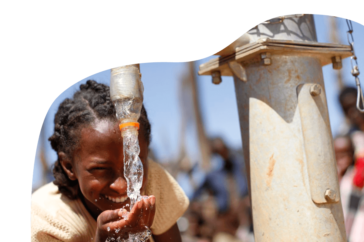 Mädchen trinkt von Wasserquelle und lächelt