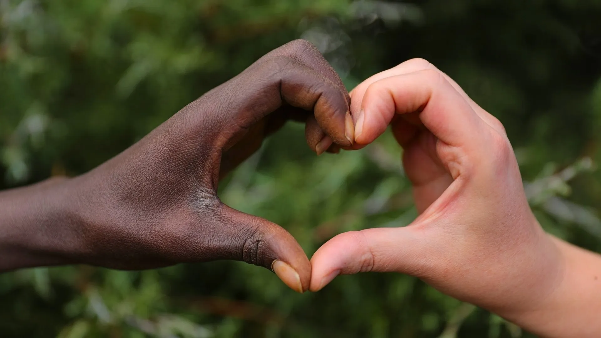 Two people are holding hands to form a heart.