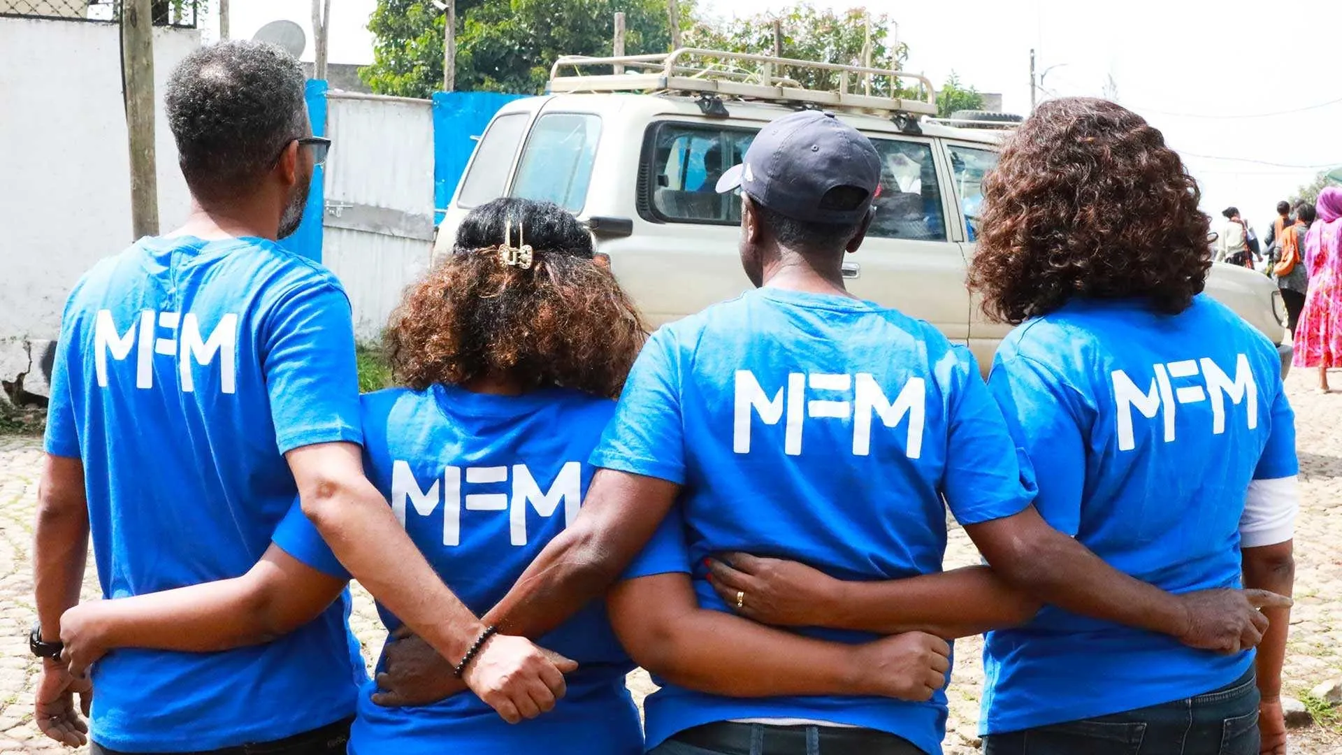 The Ethiopian team is standing arm in arm, wearing T-shirts with the organization's logo.