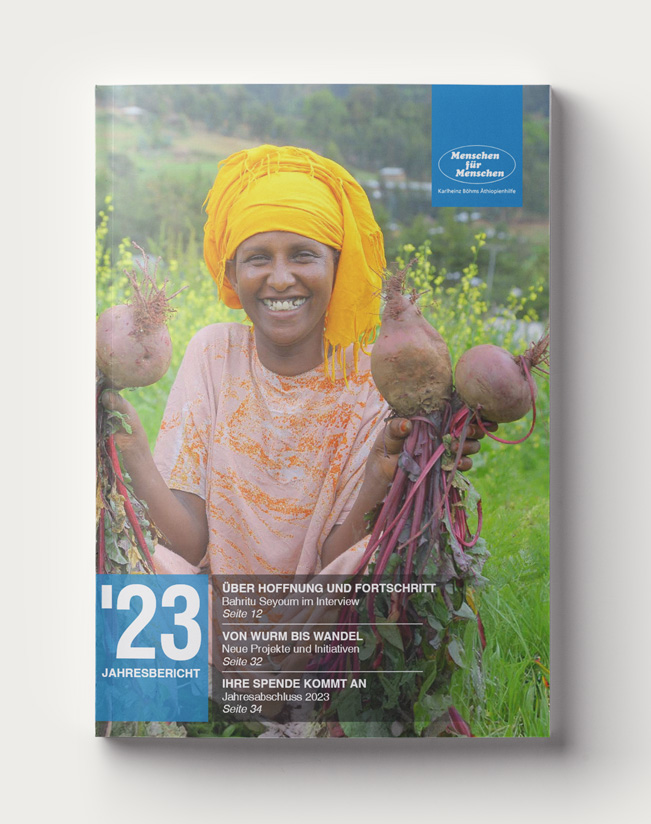 Cover of the annual report by Menschen für Menschen, which shows a woman sitting in a field, holding beets in her hand and smiling 