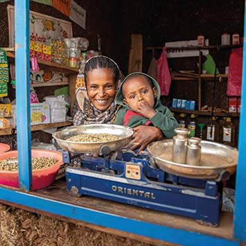 Frau mit Kind sitzt in ihrem Geschäft in Äthiopien vor einer Waage