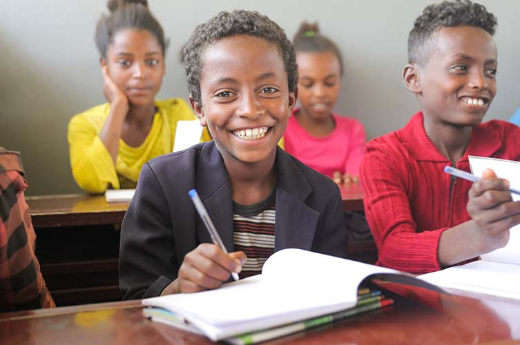 Schüler in Äthiopien grinst über seinem Buch