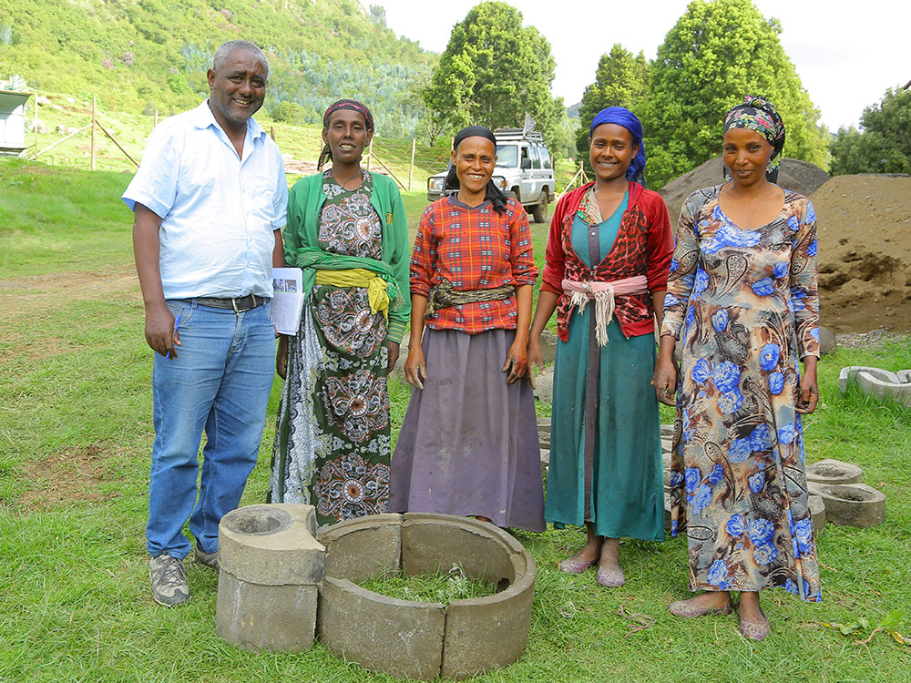 Four Ethiopian women and a man stand around an exemplary wood-saving stove made of concrete rings and look into the camera.