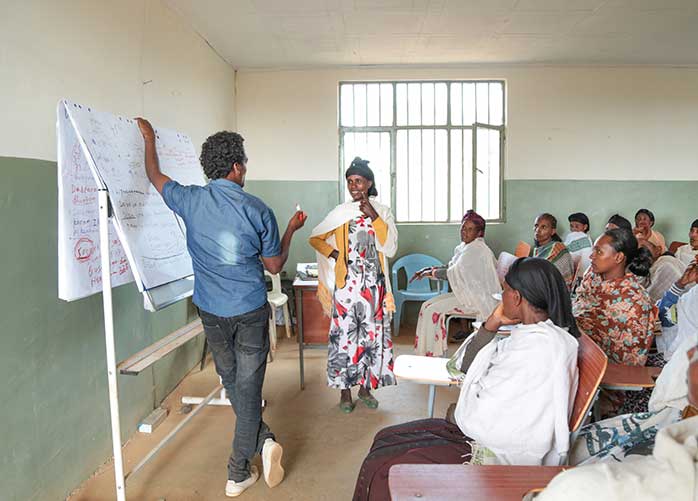 Lehrer steht in Schule in 'Äthiopien und unterrichtet Erwachsene Frauen