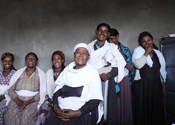 Frauen einer Kreditgruppe in Äthiopien stehen und sitzen 