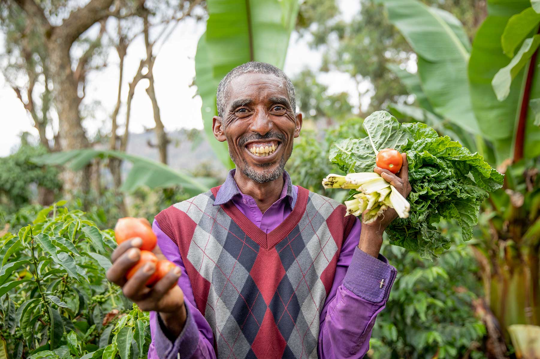 Mann lächelt und hält Gemüse in den Händen