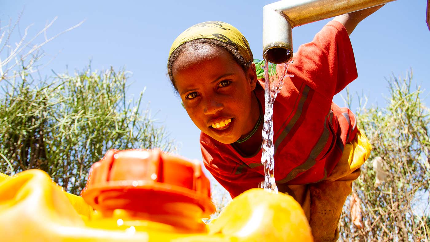 Frau an befestigter Wasserquelle von Menschen für Menschen holt Wasser