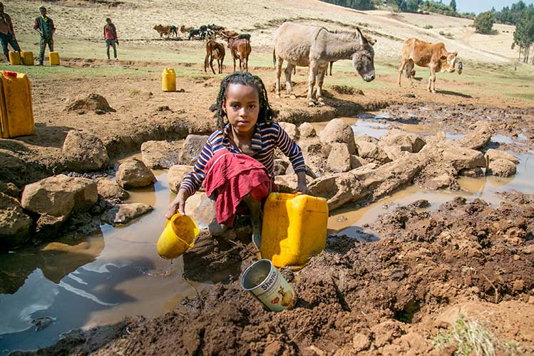 Junges Mädchen in Äthiopien beim Wasserholen an ungeschützter quelle
