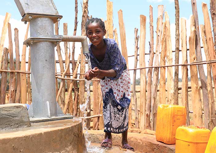 Junges Mädchen in Äthiopien beim Wasserholen in befestigter Quelle von Menschen für Menschen