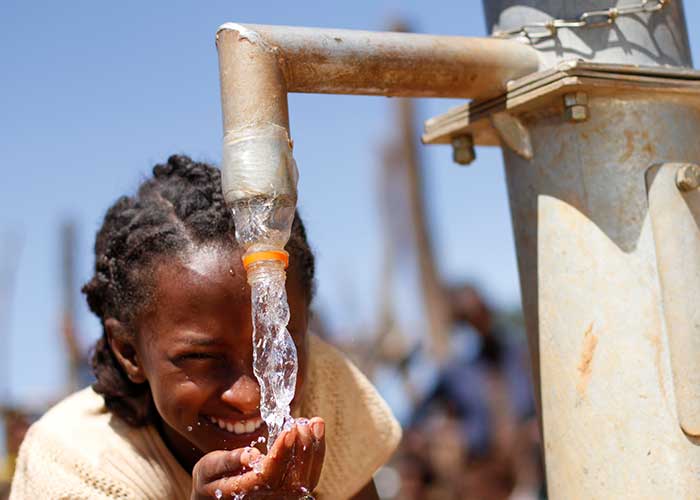 Junges Mädchen in Äthiopien beim Wasserholen in befestigter Quelle von Menschen für Menschen