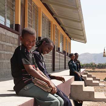 Kinder sitzen vor einer neuen Schule in Äthiopien von Menschen für Menschen
